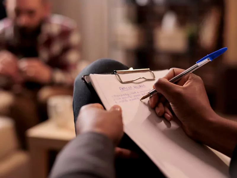 Mental health professional taking notes during a patient consultation